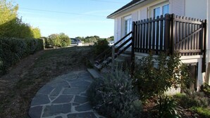 Il s’agit d’une propriété résidentielle, avec un chemin de pierre menant à une maison blanche, surmontée d’une clôture noire et agrémentée d’un escalier.