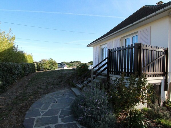 A residential property with a stone pathway leading to a white house with a black fence and a staircase.