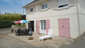 Un bâtiment à deux étages doté d’un patio aménagé avec du mobilier d’extérieur, une table et une chaise.