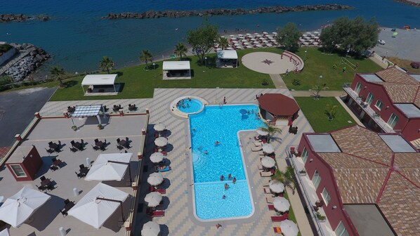 An aerial view of a resort with a central swimming pool, outdoor seating areas, and a beach area. - Hotel Valeria del Mar (Belvedere Marittimo)