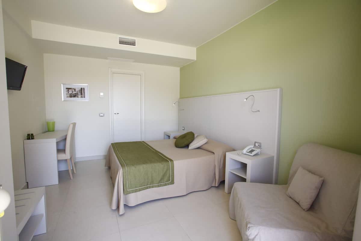 Une chambre à coucher comprenant un lit, un bureau, une chaise, une table de chevet et un téléviseur.