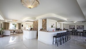A spacious living area with a central island, a sofa, and a dining area with bar stools. - Hotel Valeria del Mar (Belvedere Marittimo)