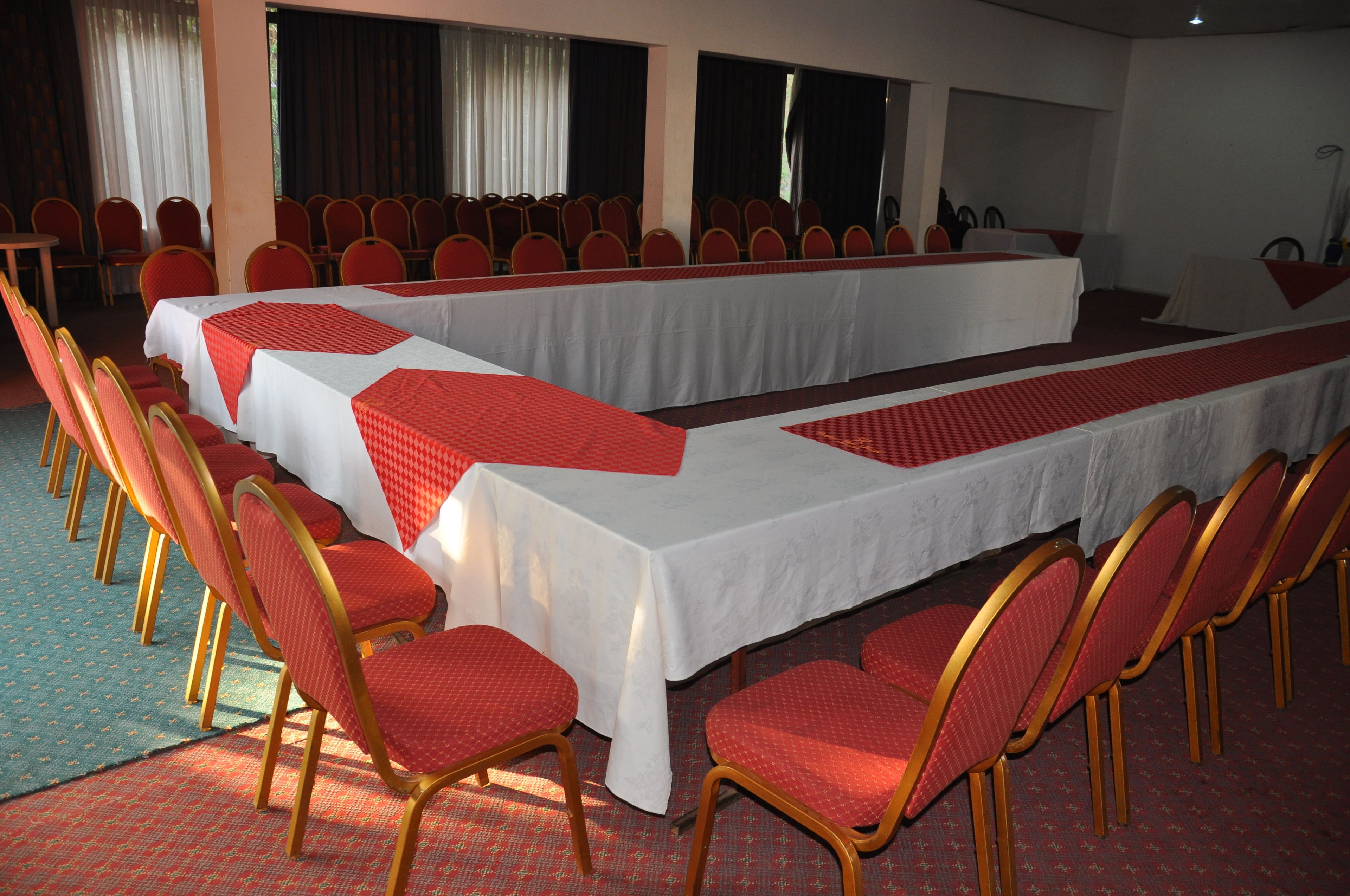 A conference room with a long table, red chairs, and white tablecloths.