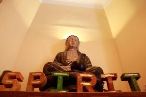 A statue of a seated figure with the word "SPIRIT" spelled out in wooden letters in front of it. - Spirit Lodge Leipzig - Hostel (Leipzig)