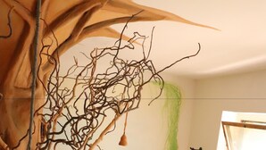 A cozy room with a large tree sculpture, a guitar player, and a person sitting on a couch. - Spirit Lodge Leipzig - Hostel (Leipzig)