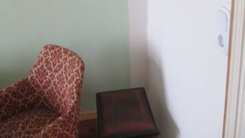 Ein Zimmer mit einem gemusterten Sessel, einem kleinen Tisch und einem Wandtrockner.