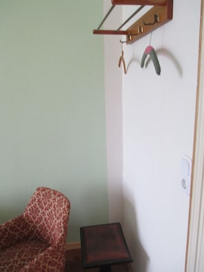 A room with a patterned armchair, a small table, and a wall-mounted drying rack. - Spirit Lodge Leipzig - Hostel (Leipzig)
