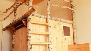 A cozy room with a wooden bunk bed, a ladder, a chair, and a table. - Spirit Lodge Leipzig - Hostel (Leipzig)
