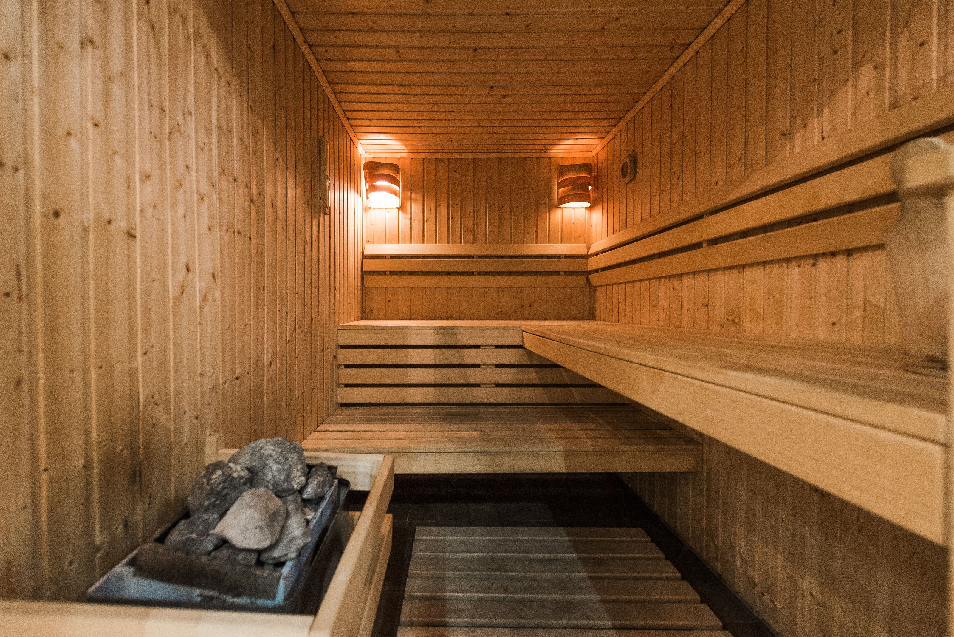 A wooden sauna with benches and a stone basin.