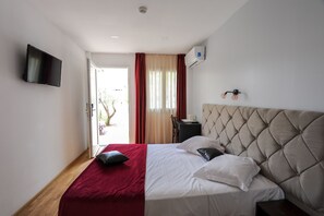 A neatly arranged bedroom with a bed, a flat-screen TV, an air conditioning unit, and a bedside table with a lamp. - HOTEL LA CITADELLE (Villefranche-sur-Mer)