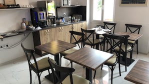 Ett modernt kök med kaffemaskin, mikrovågsugn och kylskåp. Det finns träbord och stolar som är placerade för att skapa en matplats.
