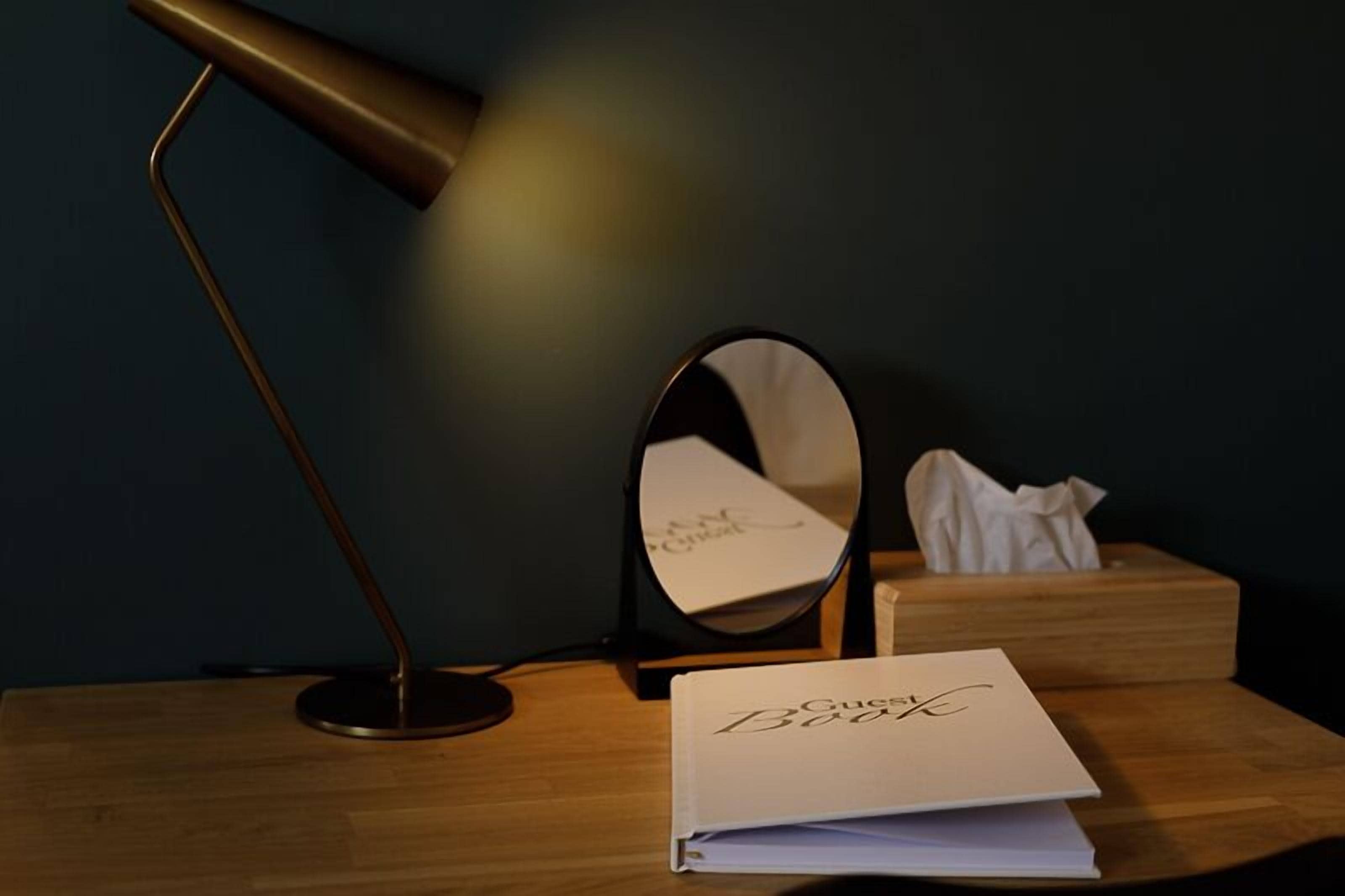 Uma mesa com um livro intitulado 'Gucci Book', uma caixa de lenços e uma luminária.