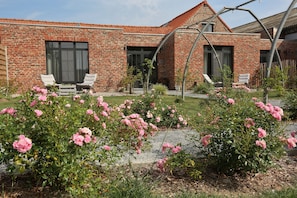 A brick house with a garden, two white chairs, and a pergola. - Herbes Folles (Steenwerck)