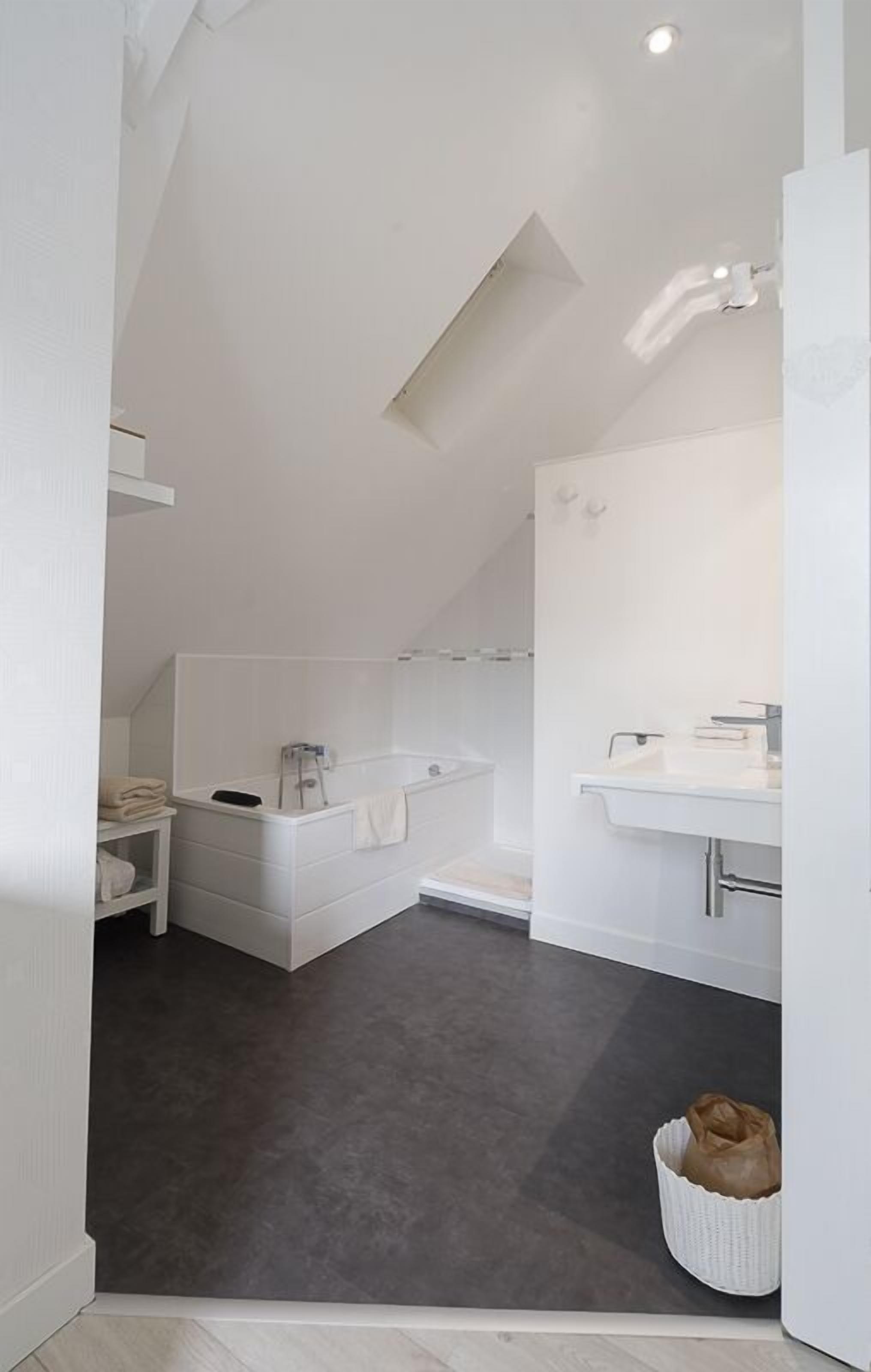 Un bagno moderno con una vasca, un lavandino e una doccia. È presente un portasciuga e un cesto a terra.