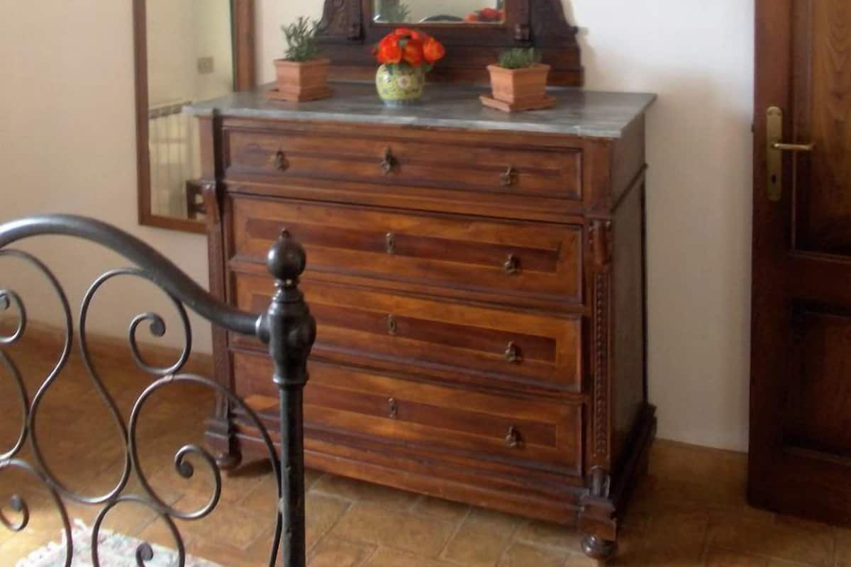 A wooden dresser with a mirror above it, flanked by two mirrors on the wall.