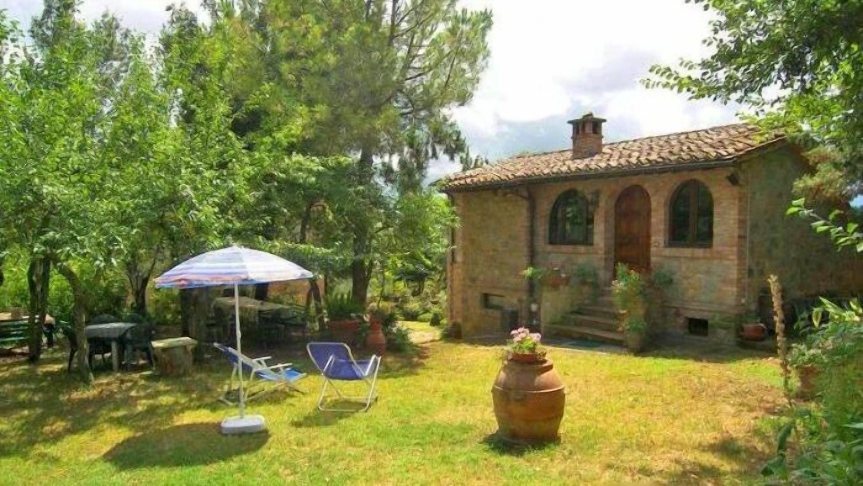 Un edificio rustico in pietra con tetto in tegole, immerso nel verde e circondato da un prato.