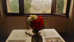 A table with a vase of flowers, a plate, and a cup. - Agriturismo Raggio di Sole (Montepulciano)