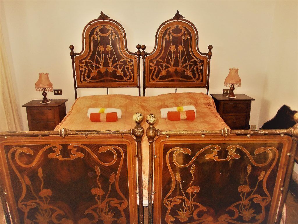Un letto con una testiera e un piedeletto elaborati, affiancati da due comodini con lampade.