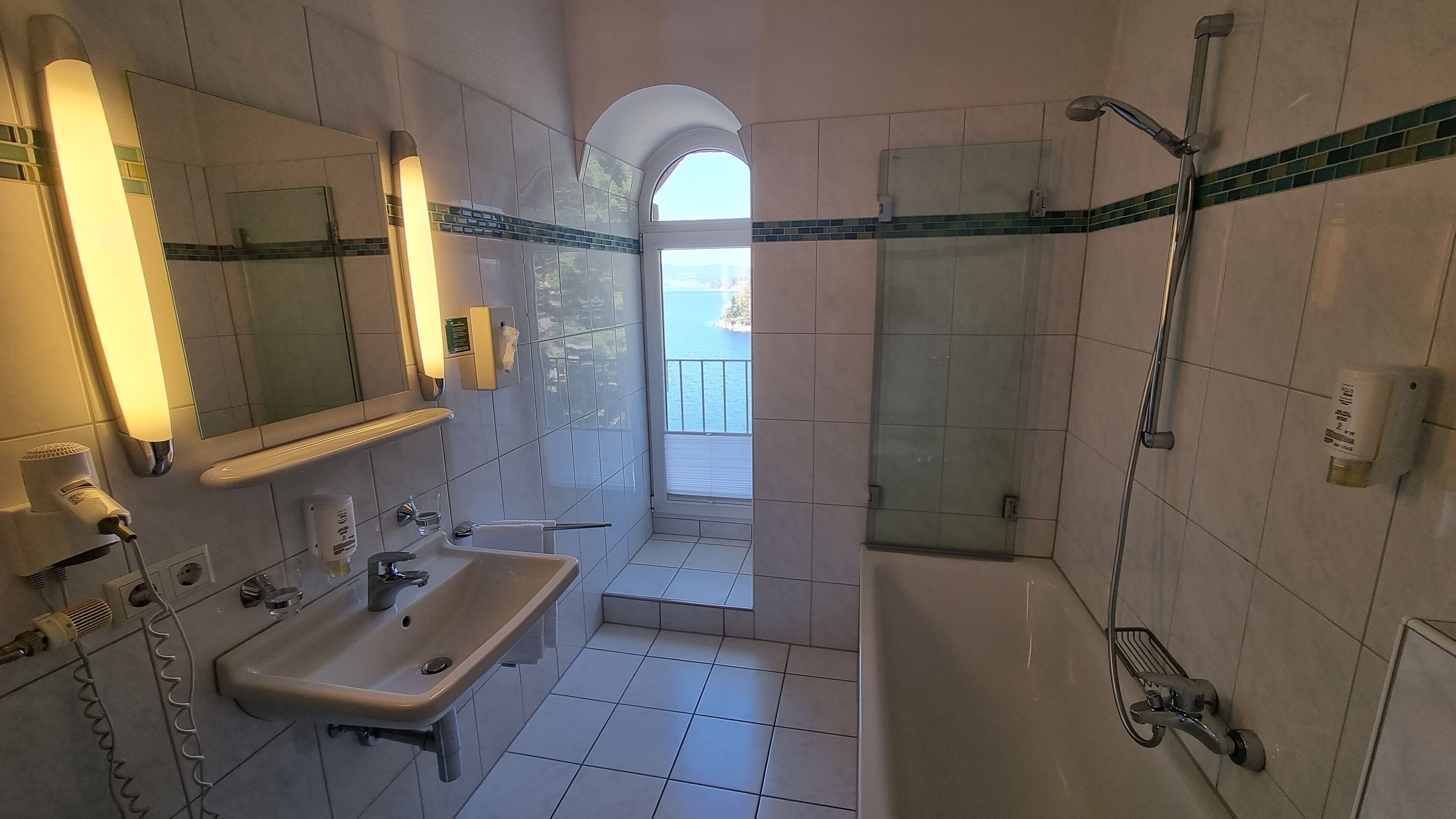 A bathroom with a sink, mirror, and shower area.