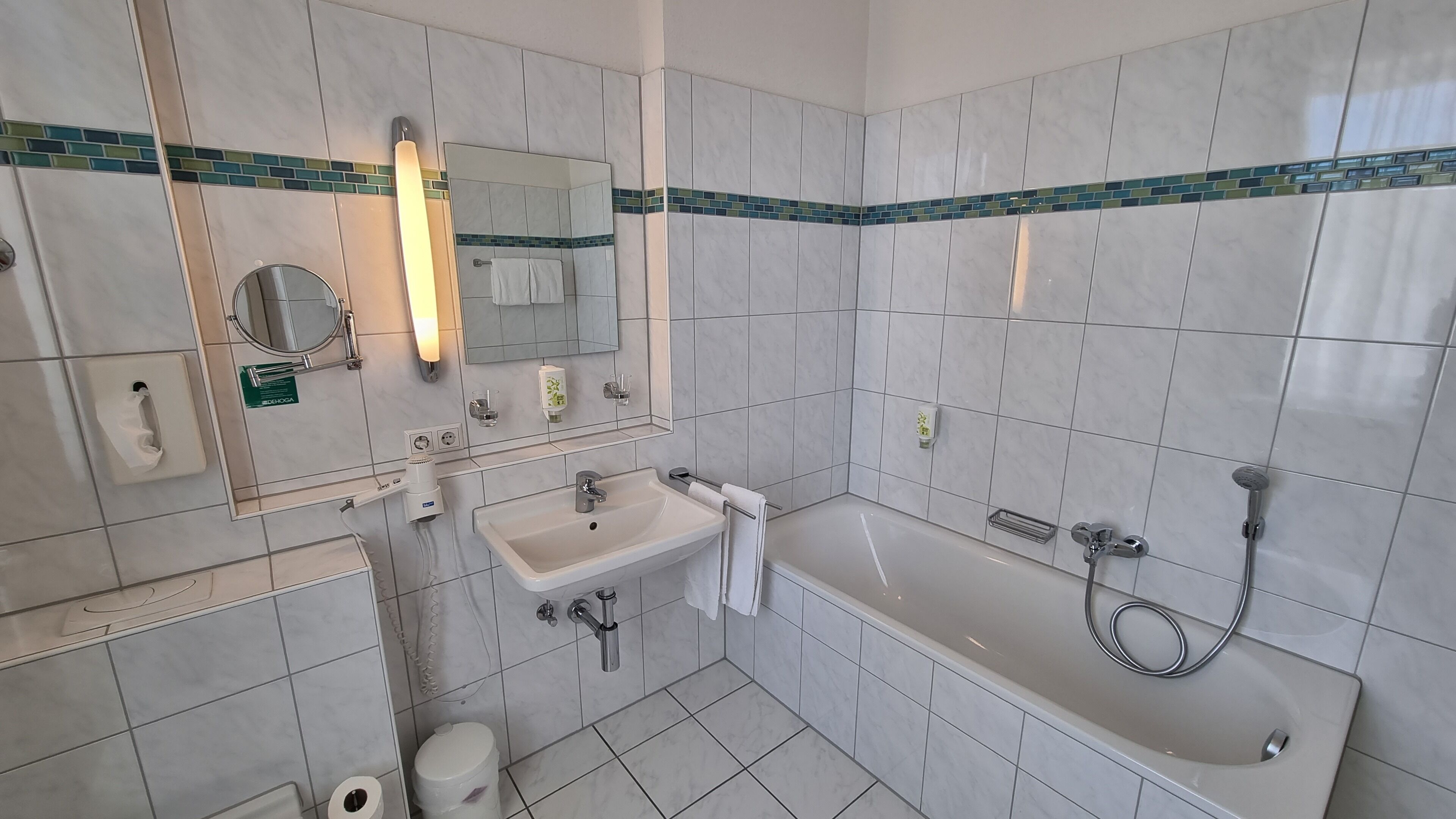 A modern bathroom with a sink, mirror, and bathtub.
