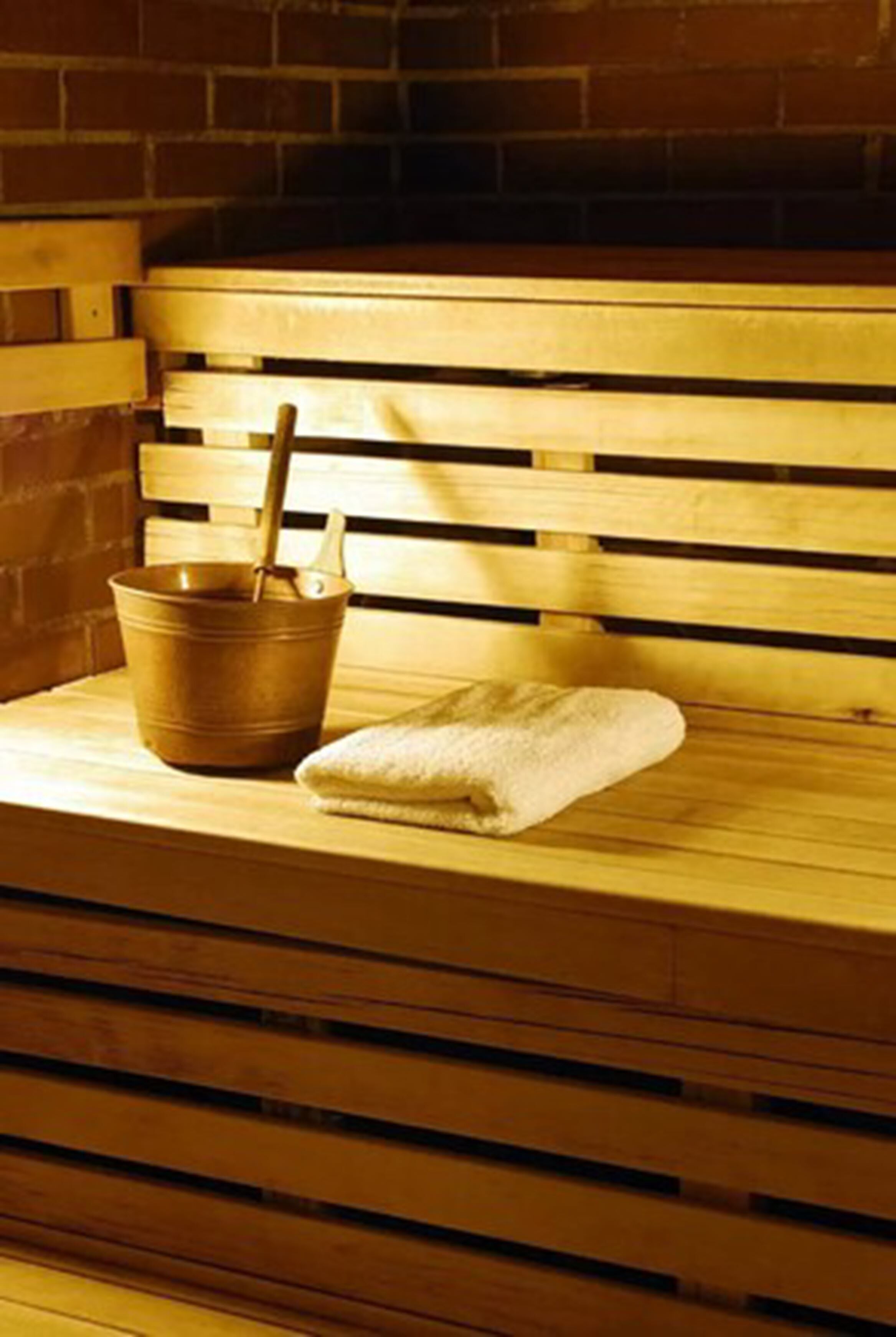 A wooden bench with a metal bucket and a towel placed on it.