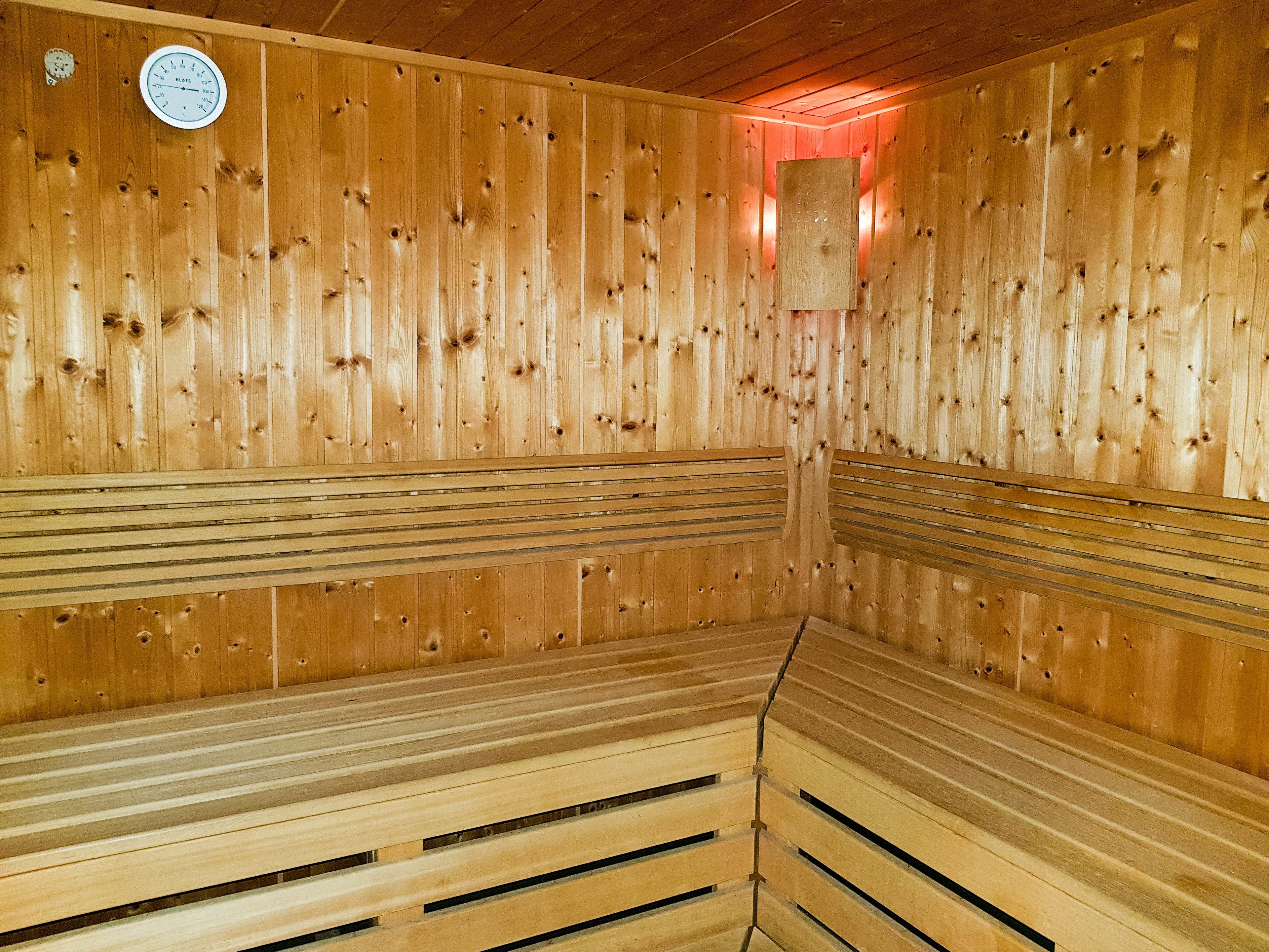 A sauna with wooden benches and a clock on the wall.