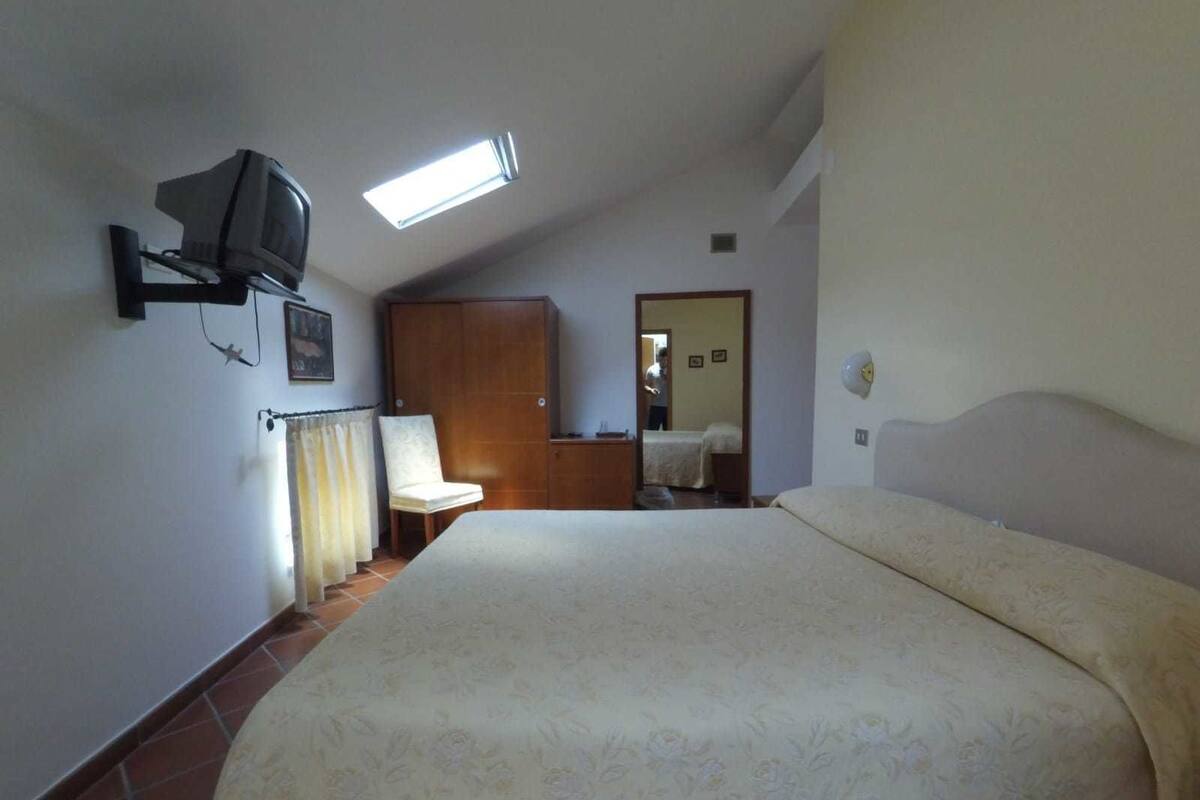 Une chambre à coucher comprenant un lit, un téléviseur fixé au mur, une armoire et un miroir.