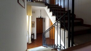 A staircase with black iron railings and a wooden handrail, leading to an upper floor. - Caterina House (San Lucido)
