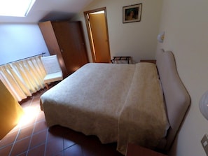 A bedroom with a bed, a door, a small table, and a window. - Caterina House (San Lucido)