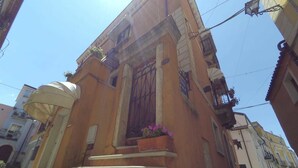 A building with a curved facade, a set of steps leading to the entrance, and a balcony with potted plants. - Caterina House (San Lucido)