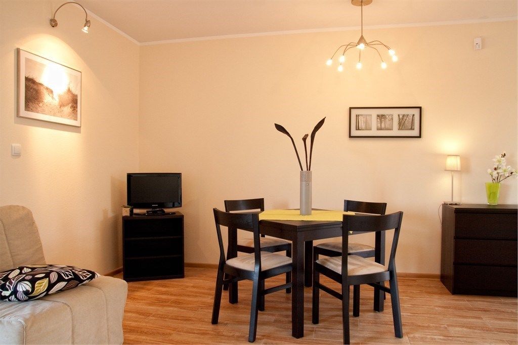 A dining area with a table and chairs, a television on a stand, and artwork on the walls.
