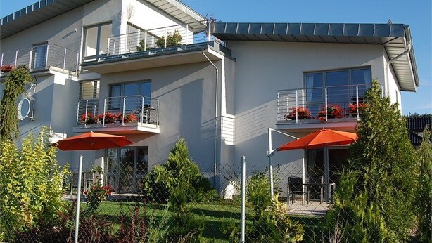 A modern two-story building with balconies, outdoor seating, and a well-maintained garden. - Willa Pod Cyprysami (Ustka)