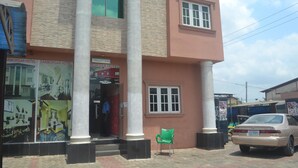 A hotel with a large entrance, a green chair outside, and a parked car. - Dan Morgan Hotel & Suites (Lagos)