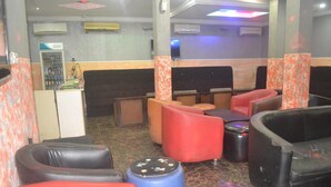 A seating area with various chairs and stools, air conditioning units, and a small counter. - Dan Morgan Hotel & Suites (Lagos)