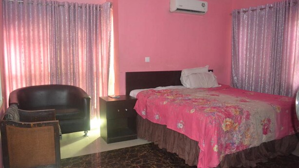 A bedroom with a bed, a nightstand, a chair, and a sofa. - Dan Morgan Hotel & Suites (Lagos)
