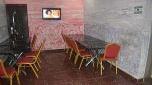 A conference room with a glass table, red chairs, a television on the wall, and a prohibition sign for smoking. - Dan Morgan Hotel & Suites (Lagos)
