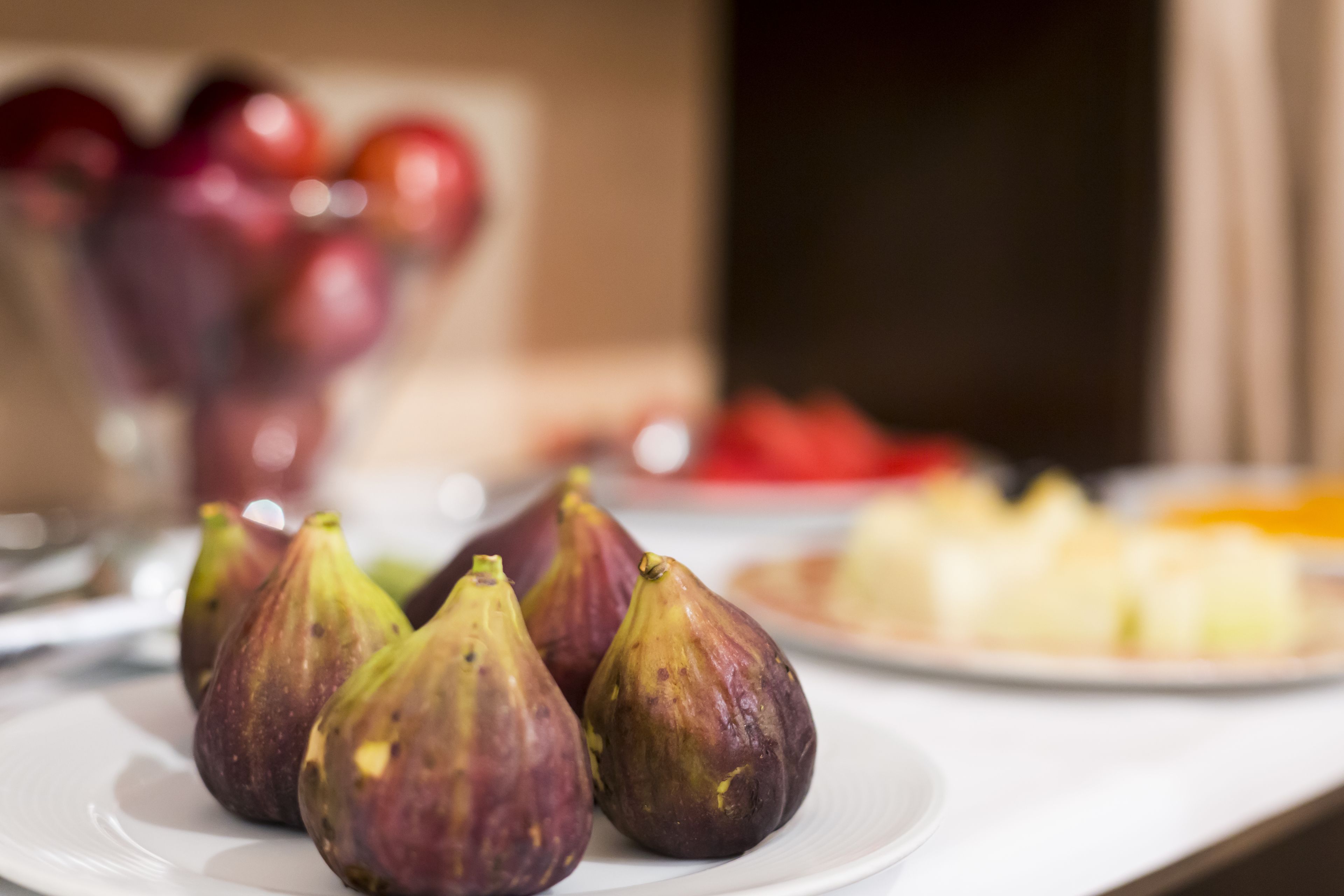 Une assiette de figues sur une table blanche, avec un arrière-plan flou.