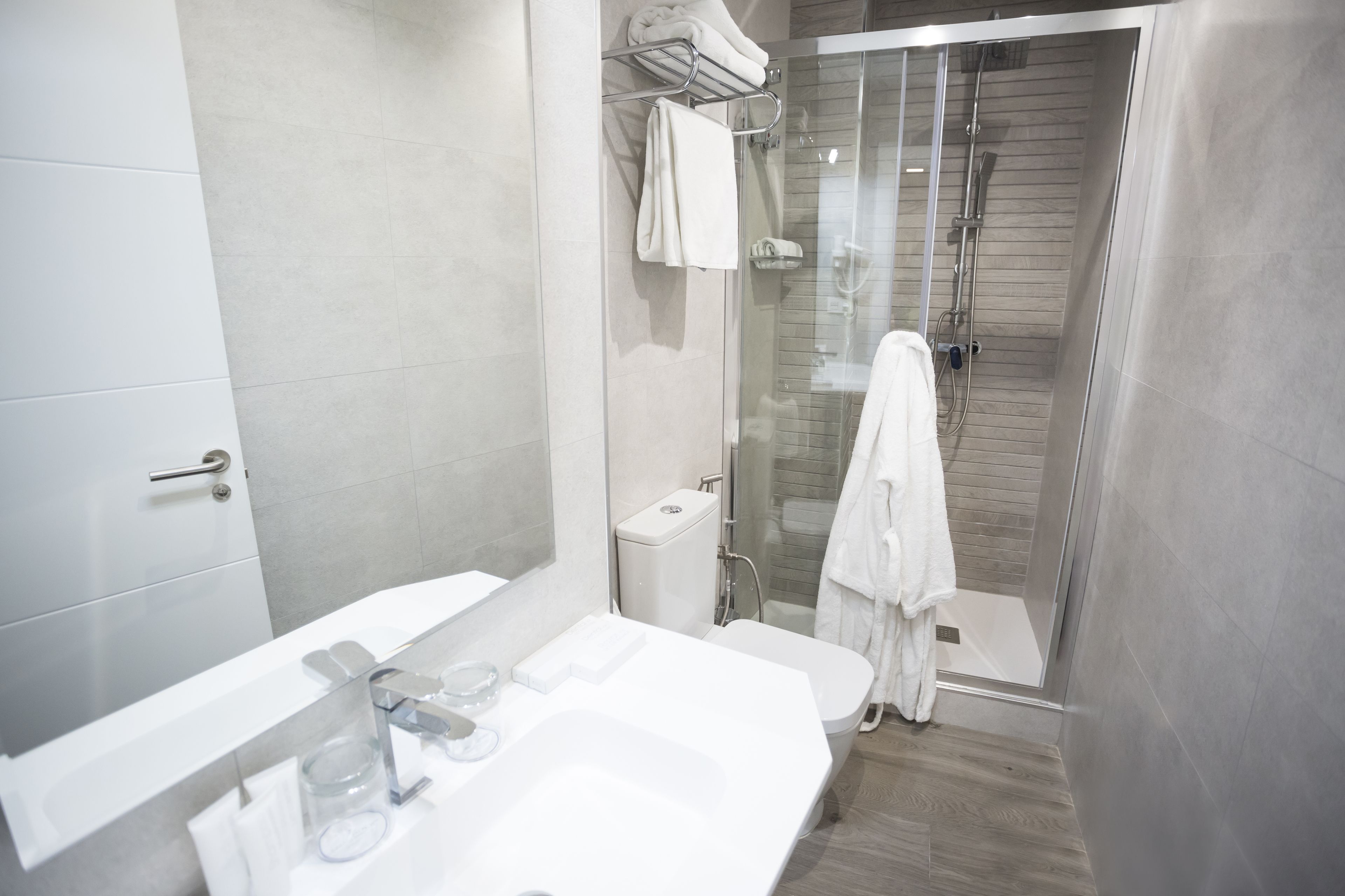 Un baño moderno con ducha de vidrio, un lavamanos blanco y un inodoro.