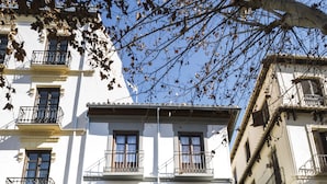 Une vue de rue avec un immeuble doté de nombreuses fenêtres et de balcons, un passage piéton et des bollards le long du trottoir.