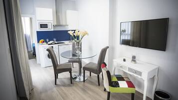 Una cocina moderna con microondas, estufa y lavaplatos. Hay una mesa de comedor con sillas y un televisor en la pared.