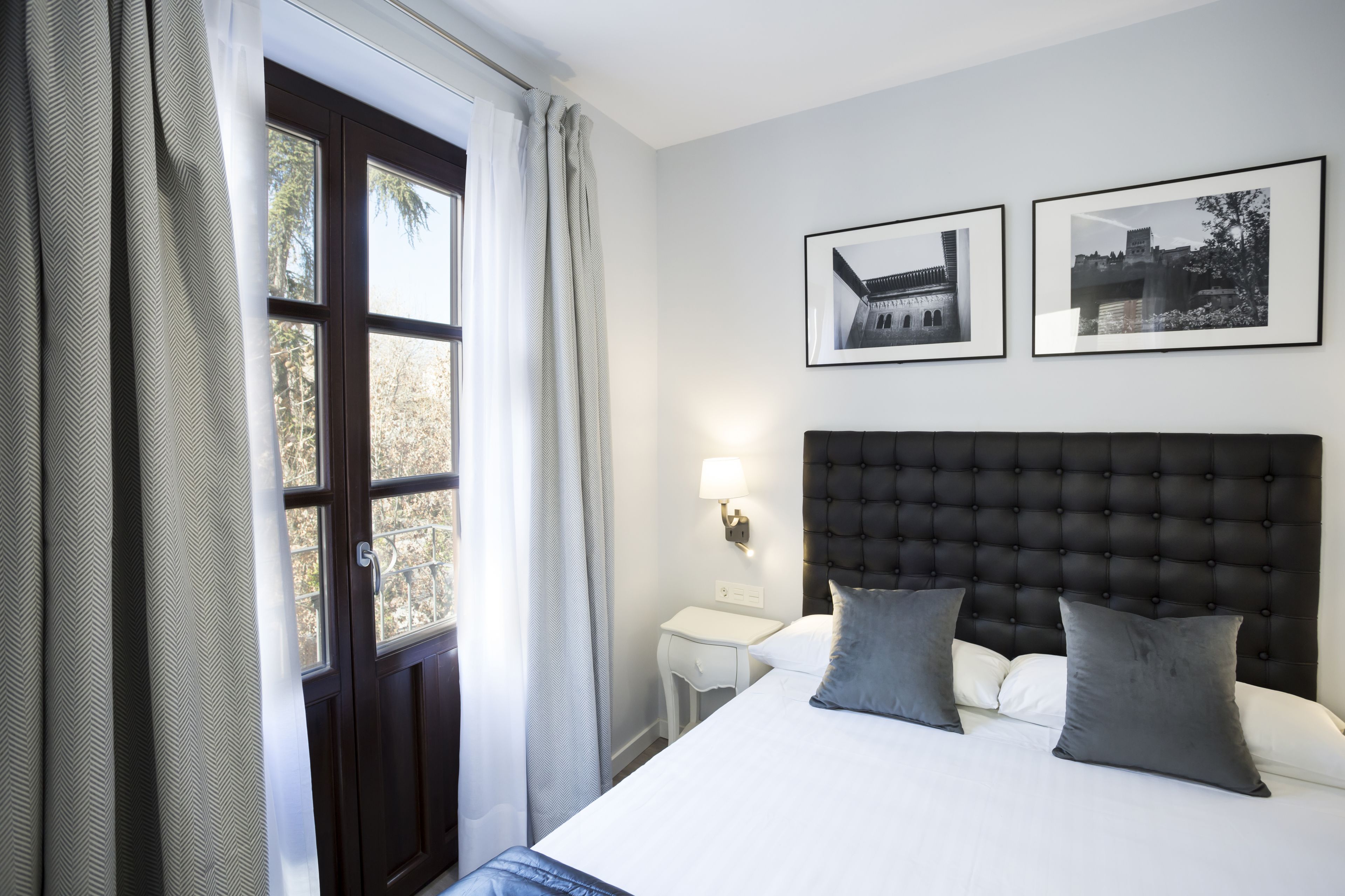Une chambre d’hôtel avec un grand lit, deux oreillers, une table de chevet avec une lampe et deux tableaux encadrés au mur.
