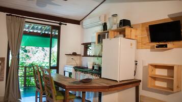 Una cocina con una mesa de comedor, sillas, un refrigerador, un microondas, una estufa y un televisor montado en la pared.