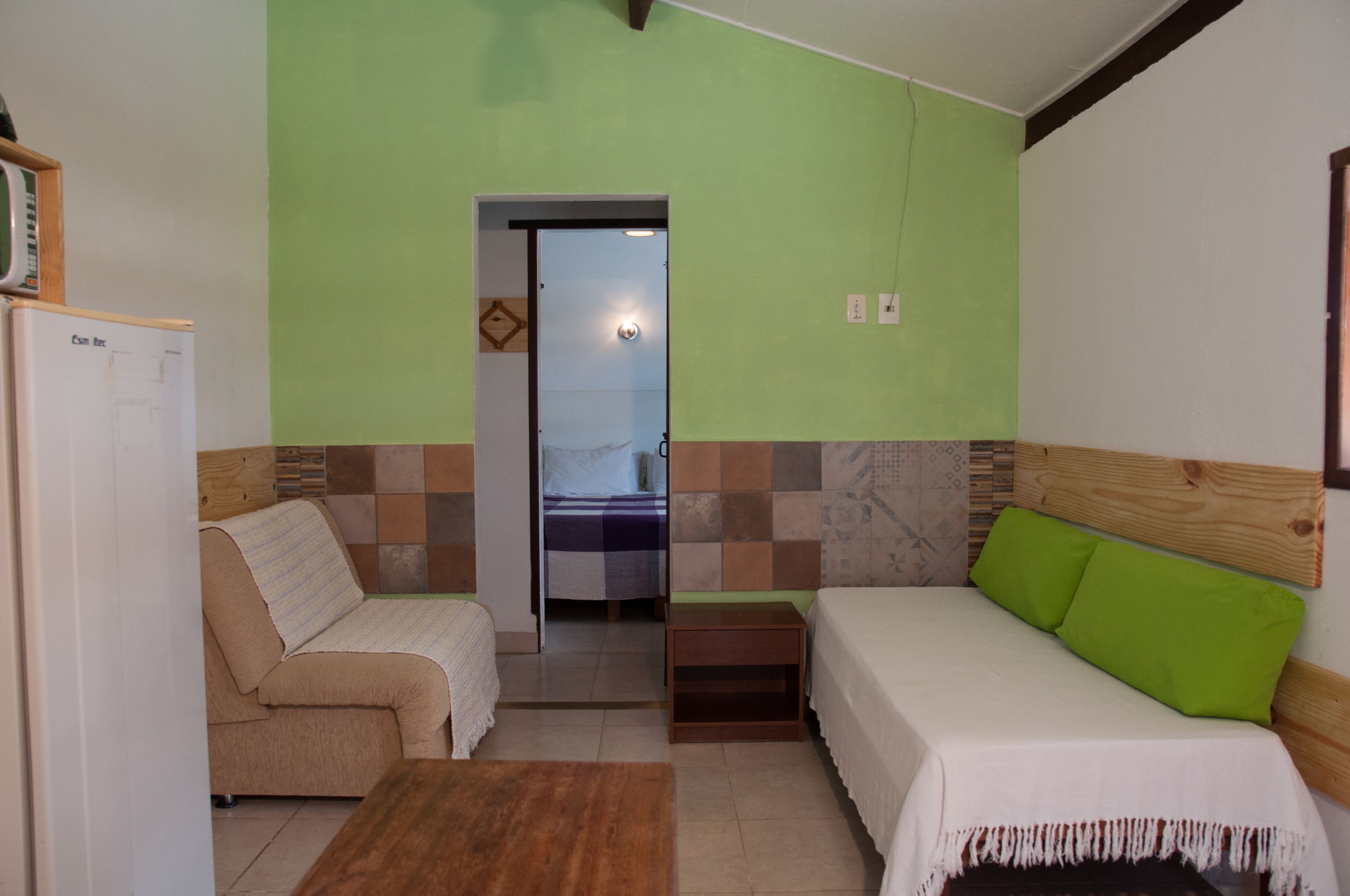 Una habitación con una cama, un sofá, una mesita y una puerta que da a un baño.