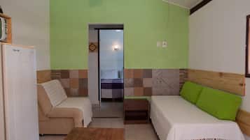 Una habitación con una cama, un sofá, una mesita y una puerta que da a un baño.