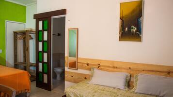 A room with a bed, a wooden headboard, a mirror, and a painting on the wall.