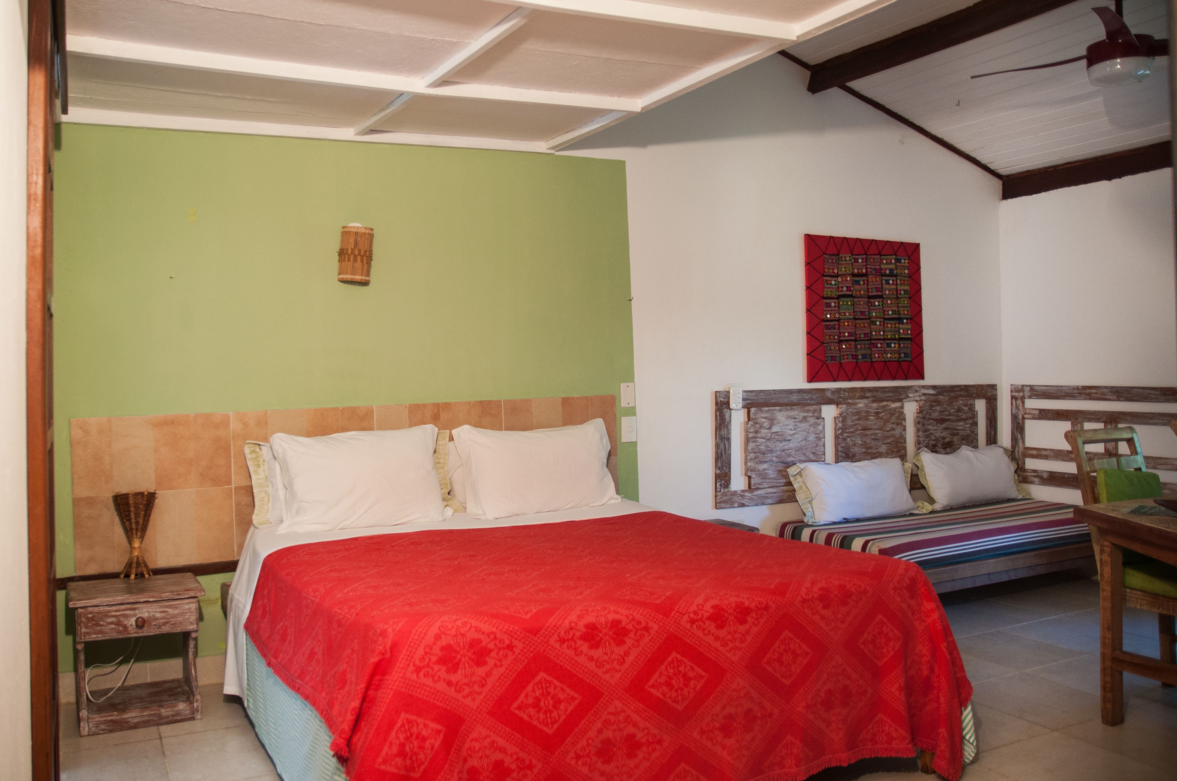 Una habitación con una cama grande, una cama más pequeña, una mesita de noche de madera y una silla.