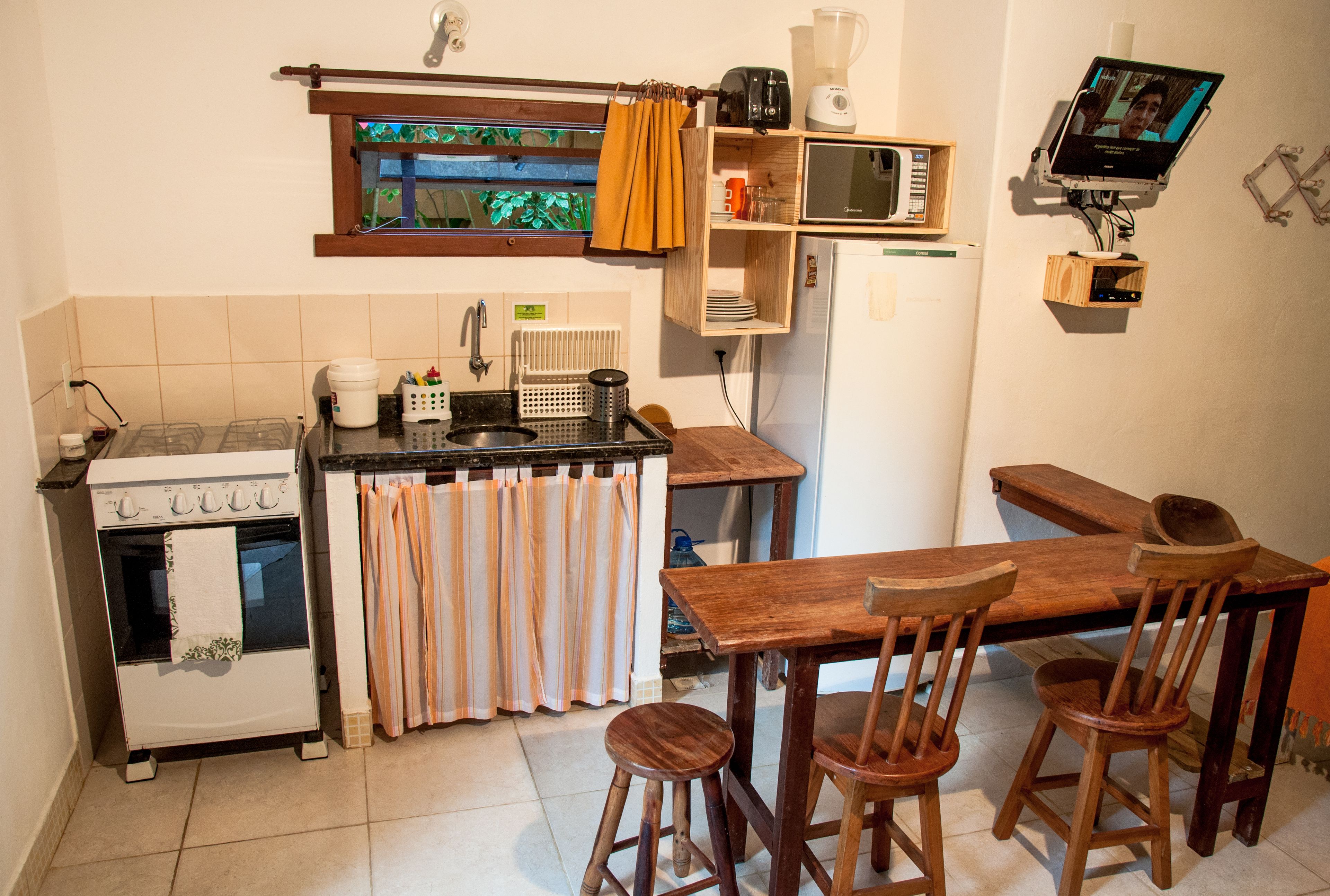 A compact kitchen with a stove, microwave, and wooden dining table.