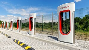 A row of Tesla charging stations with a clear sky and greenery in the background. - Hôtel Akena Besançon (Chemaudin)