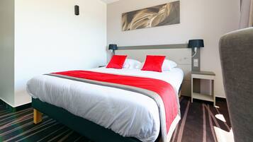 Ein Hotelzimmer mit Bett, Nachttisch, Lampe und Stuhl.