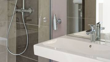 Un baño con ducha, lavabo y espejo.